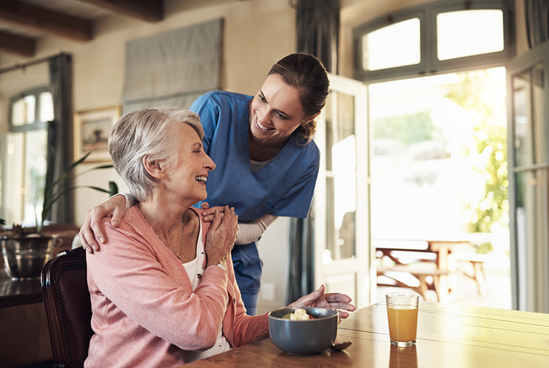 Caregiver checking in on a senior resident during mealtime