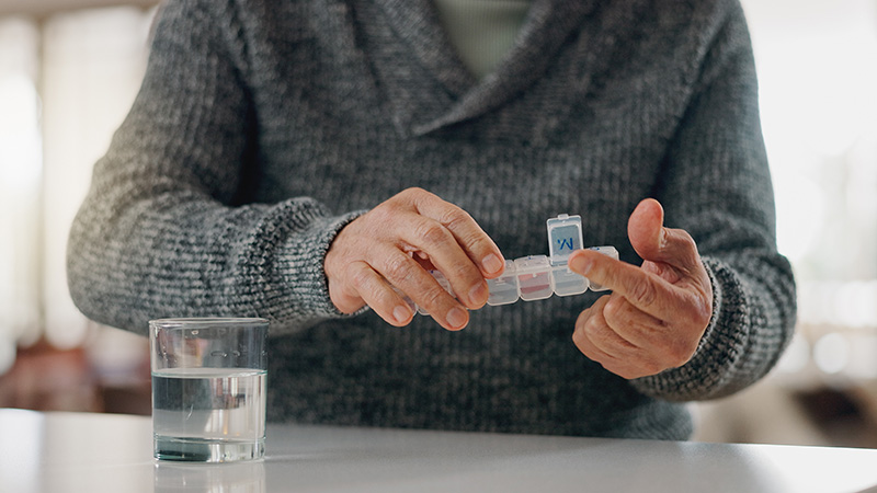Senior resident managing daily medications with a pill organizer and glass of water