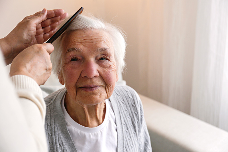 Caregiver brushing a senior resident's hair as part of personal care assistance