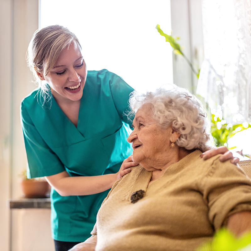 Smiling caregiver checking in on a senior resident during daily care