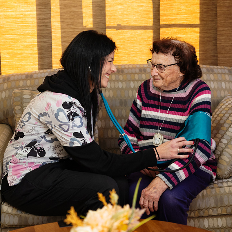 Caregiver taking a resident's blood pressure during a wellness check