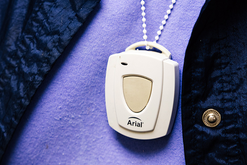 Personal emergency call pendant worn by a resident for 24-hour safety monitoring