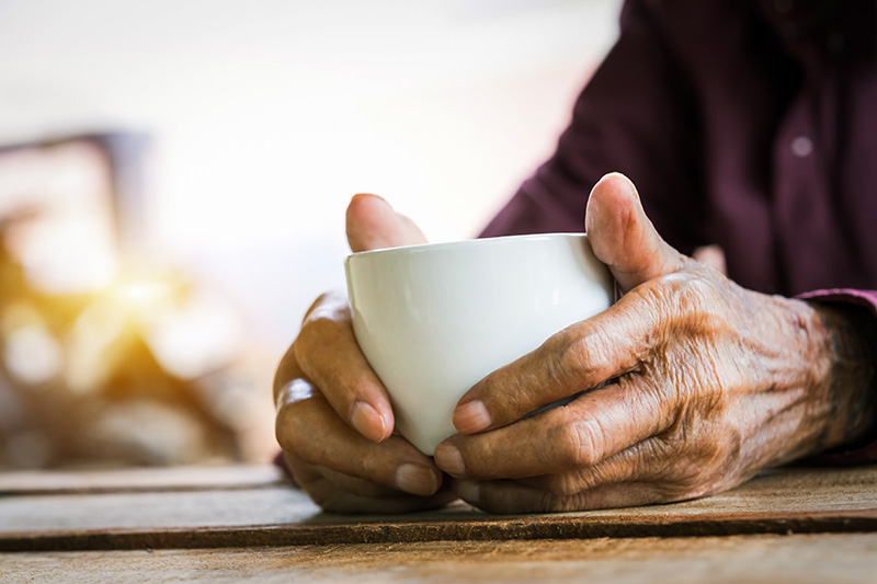 Senior resident's hands cradling a warm cup of coffee