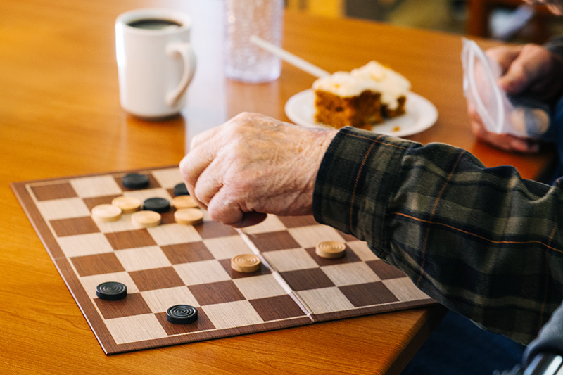 Senior resident playing checkers during a social activity at an assisted living commun