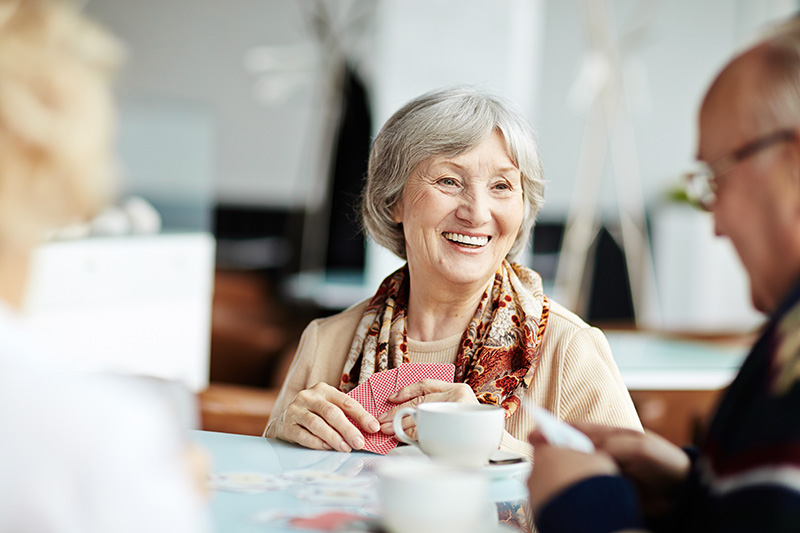 Senior resident smiling and socializing over coffee in a common area