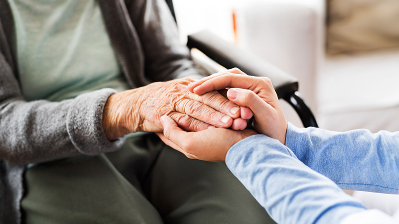 Caregiver holding the hands of a senior resident at Cornerstone Residence of Oklee