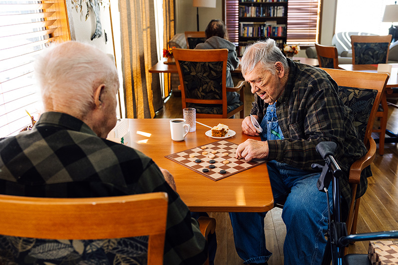 Two residents playing checkers in the common dining area at Cornerstone Residence of Oklee