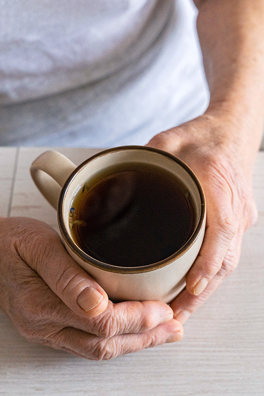 Senior resident's hands wrapped around a warm cup of coffee